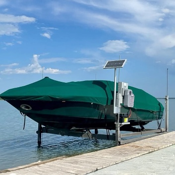 Covered boat on a solar-powered boat lift on Smith Lake, Alabama, with a solar panel and control box mounted on the lift post