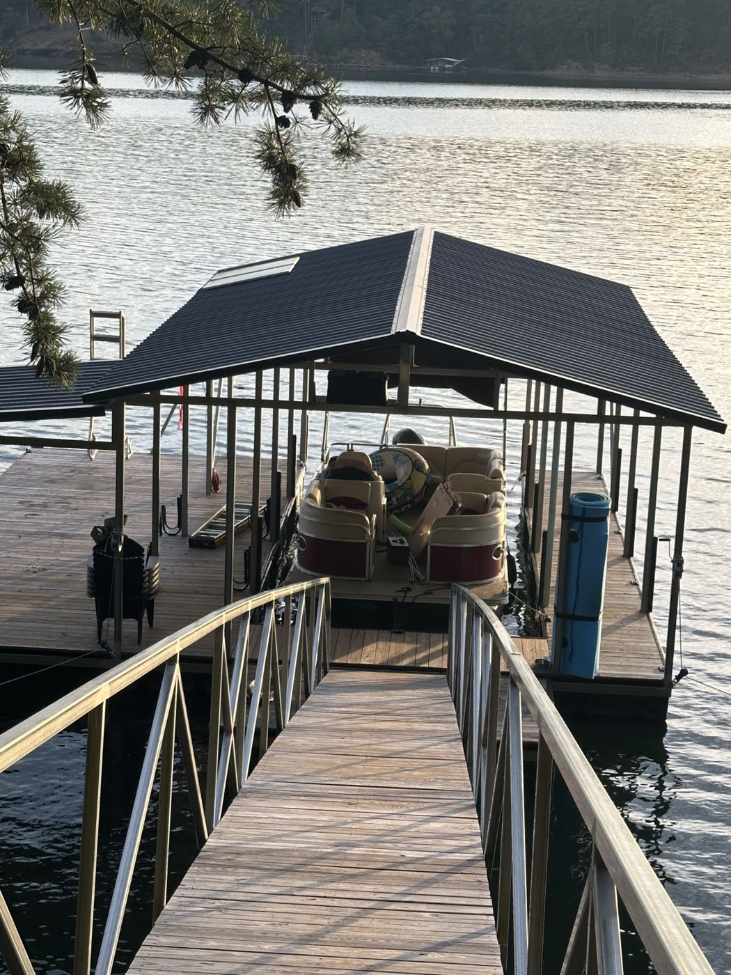 Covered boat dock with pontoon boat on Smith Lake at golden hour, powered by dock solar