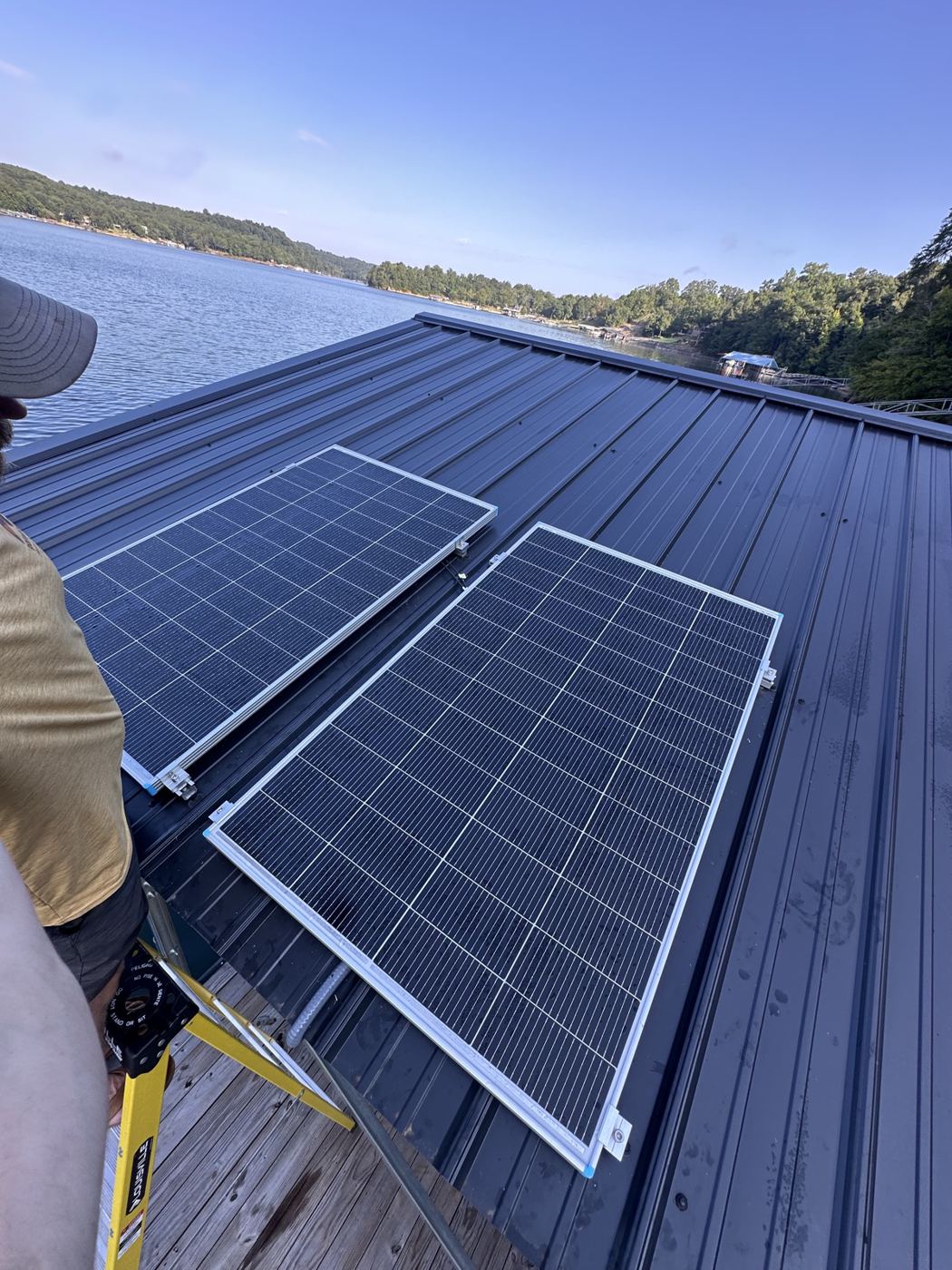 Solar panels being installed on a metal boathouse roof over Smith Lake, Alabama